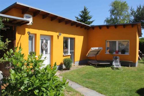 LassanFerienhaus Lassan VORP 2631的一座黄色和橙色的小房子,有院子