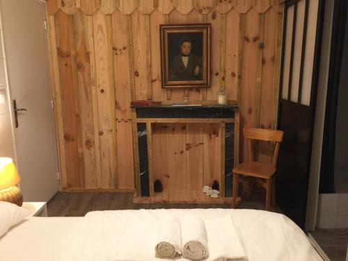 卡普费雷Hôtel Le Caillebotis的卧室配有一张床,还展示了一张男人的照片