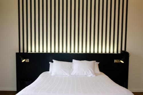 穆瓦萨克穆瓦萨克穆勒Spa酒店 的一张带黑色床头板和白色枕头的床