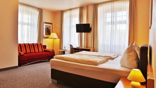阿尔蔡施洛斯酒店的酒店客房,配有一张床和一张红色的沙发