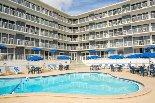 德通纳海滩海岸Sea Club IV Resort的酒店前的游泳池配有椅子和遮阳伞