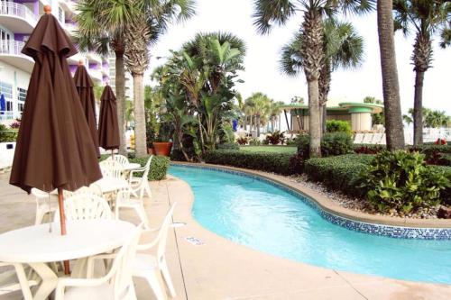 代托纳海滩Ocean Walk Resort 603的度假村的游泳池配有桌子和遮阳伞