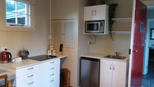 奥玛鲁Little Red School House的厨房配有白色橱柜、水槽和微波炉