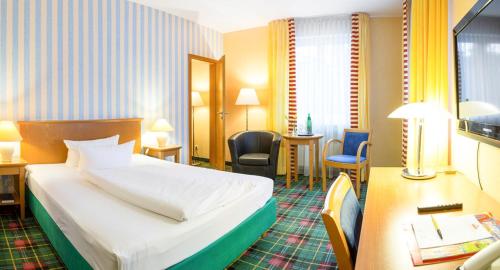 柏林Grünau Hotel的配有一张床和一张书桌的酒店客房