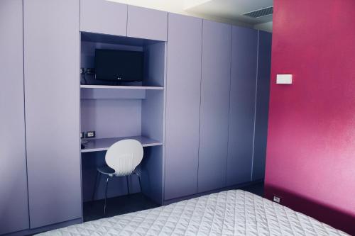 圣阿尔坎杰洛-迪罗马涅Villa Greta的一间设有紫色墙壁、白色椅子和电视的客房