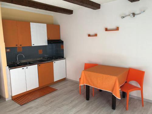 CraveggiaAlbergo La Perla的一间带桌子的厨房和一间带橙色和白色橱柜的厨房
