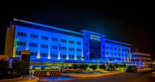 延布延布阿尔巴哈诺富特酒店的夜间有蓝色灯光的建筑的酒店
