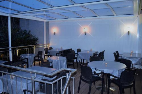 巴塞尔Hotel Locanda的阳台餐厅,配有白色的桌椅