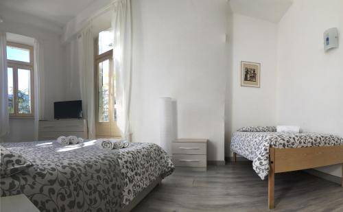 卢加诺卢加诺佛伦西酒店的一间白色卧室,配有两张床和电视