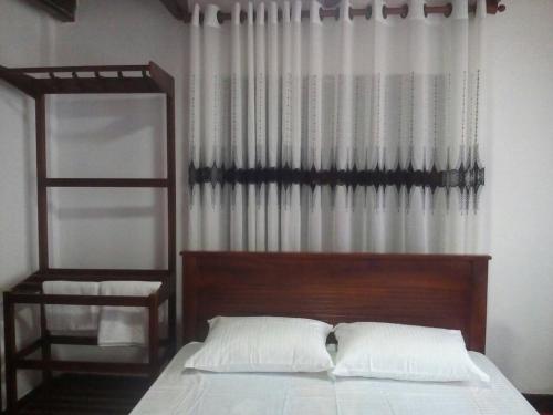 马特莱Walawwa Guest House的一间卧室配有一张带木制床头板的床和窗户。