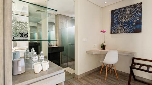 塞米亚克巴厘岛塞米亚克道恩酒店的一间带玻璃淋浴和白色椅子的浴室