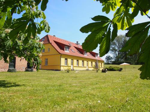 京斯特Ferienhaus Gut Rattelvitz Insel Rügen的田野上红色屋顶的黄色房子
