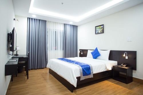 胡志明市索莱克斯酒店的一间卧室配有一张床、一张书桌和一台电视