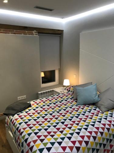 巴利亚多利德AIRVA: Apartamento Duque de la Victoria的一间卧室配有一张大床和色彩缤纷的毯子