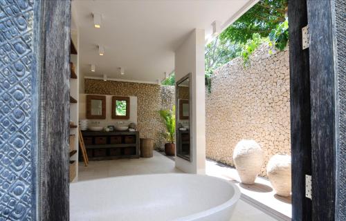 佩母德兰Jeda Villa Modern Stylish Luxury Villa的带浴缸和石墙的浴室。