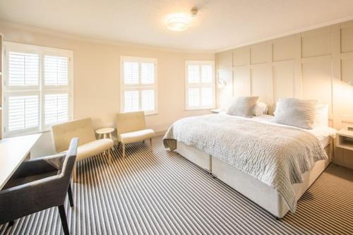 圣马丁格恩西Les Douvres Hotel的卧室配有一张床、一张桌子和椅子