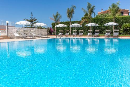 迪亚曼特Hotel Ferretti的一个带椅子和遮阳伞的大型蓝色游泳池