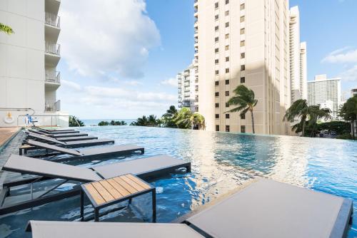 檀香山威基基海滩阿洛希拉尼酒店的一座带躺椅的游泳池以及建筑