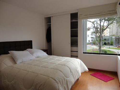 利马Miraflores Bello Apartamento的一间卧室设有一张大床和一个大窗户