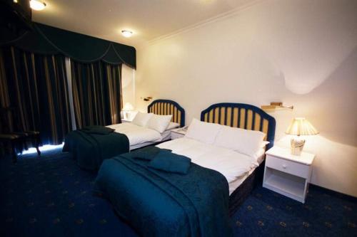 耶路撒冷阿达酒店的酒店客房设有两张床、一张桌子和灯具。