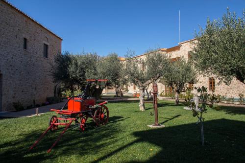 米斯特拉斯Mystras Grand Palace Resort & Spa的坐在建筑物旁边的草上的一个红色马车