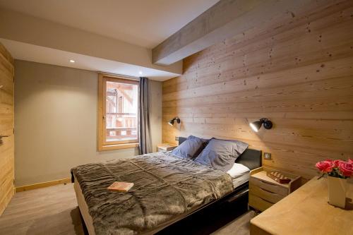 拉普德兹Odalys Chalet Nuance de gris的一间卧室设有一张床和木墙