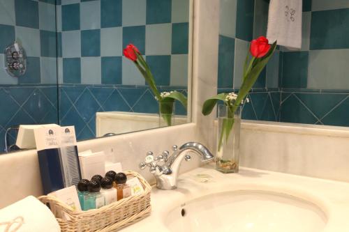 马德里拉奎因塔德罗斯塞德罗斯酒店的浴室水槽,花瓶里放着两朵红花