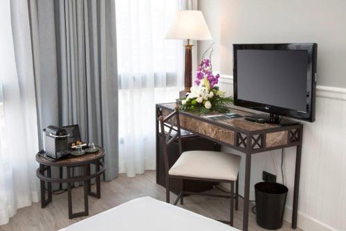 洛格罗尼奥格兰维亚酒店的酒店客房配有带电视和鲜花的书桌