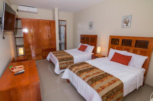 塔拉波托La Floresta Tarapoto Hostal的酒店客房设有两张床和电视。