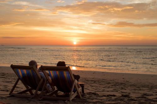 高兰Isara Lanta Beach Resort的两人坐在沙滩椅上,欣赏日落