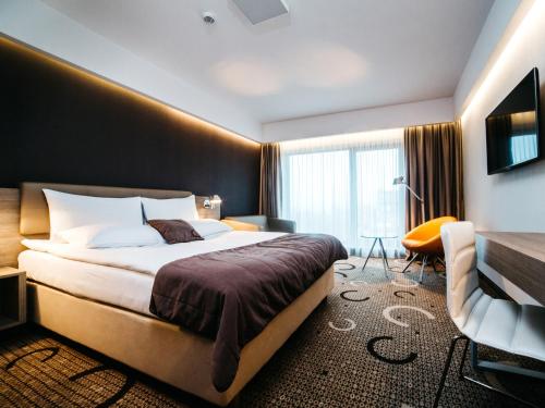 克拉科夫克拉科夫普鲁斯Q酒店的配有一张床和一把椅子的酒店客房