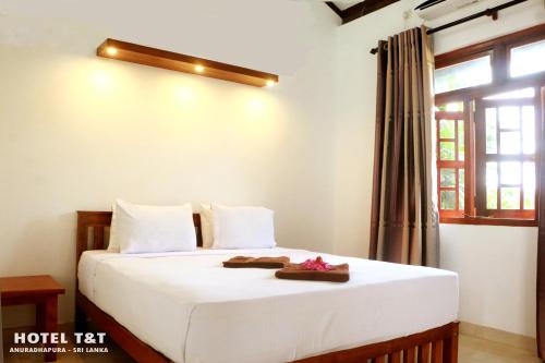 阿努拉德普勒T&T酒店的一间卧室配有一张带白色床单的床和一扇窗户。