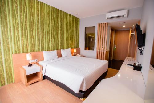 雅加达快乐驿站酒店的一间卧室配有一张大床和电视