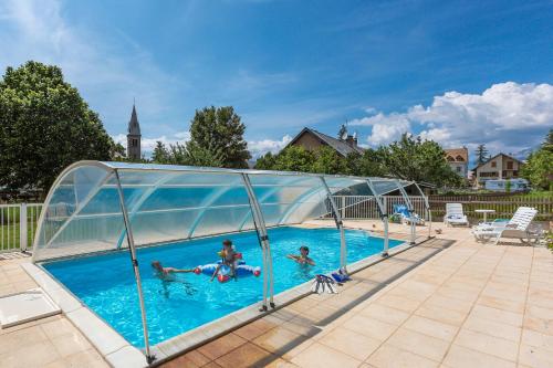 昂塞勒Hotel restaurant Le Chamois的一群人在一个带玻璃围墙的游泳池游泳