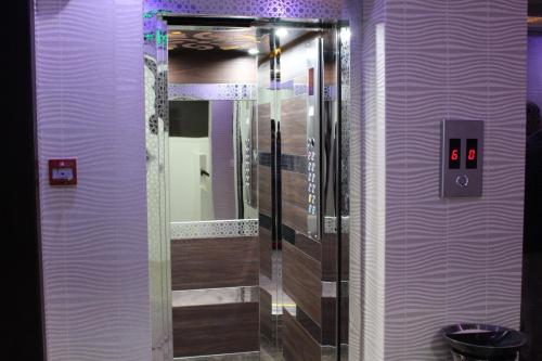 利雅德Sama Hotel的带淋浴、镜子和紫色墙壁的浴室
