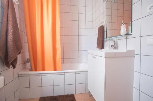 大塔拉哈尔Apartamento con ascensor en primera línea的浴室内配有橙色淋浴帘和水槽