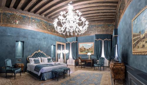 威尼斯纳尼莫切尼戈宫酒店的一间卧室设有蓝色的墙壁和吊灯。