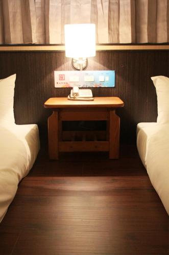 马公丰谷大饭店  的一张桌子,上面有灯,旁边是两张床