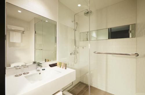 首尔江南区COEX中心GLAD酒店的白色的浴室设有水槽和淋浴。