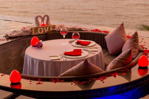 卡马拉海滩Cape Sienna Phuket Gourmet Hotel & Villas - SHA Extra Plus的一张桌子,上面放着酒杯和红花