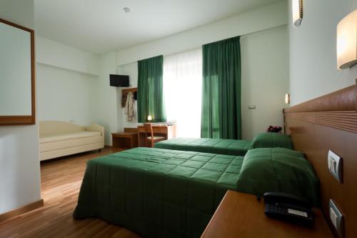阿西西唐尼尼酒店的一间卧室配有两张绿色的床和一张沙发