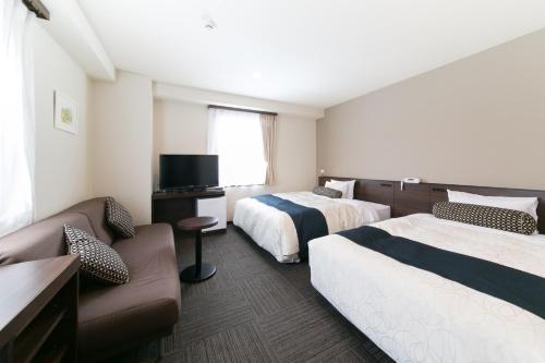 青森Aomori Center Hotel的酒店客房,设有两张床和一张沙发