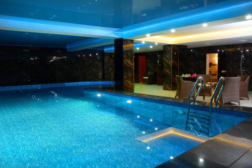塔拉兹Hotel Arai Plaza的大楼内带蓝色灯光的游泳池