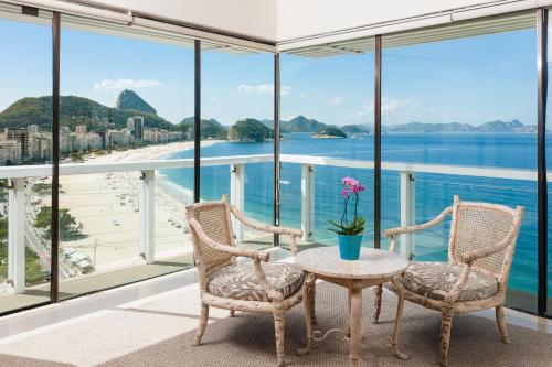 里约热内卢里奥安托宫殿酒店的阳台配有桌椅,享有海滩美景。