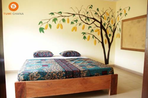 库马西Tumi Hostel的卧室配有一张墙壁上涂有树的床铺。