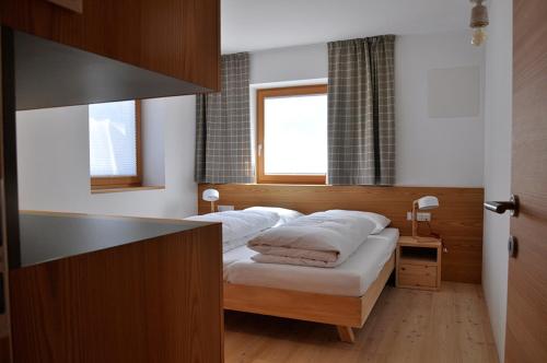 瓦尔道拉Apartments Frieda的一间卧室配有一张带白色床单的床和一扇窗户。