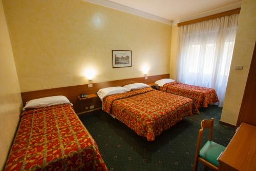 罗马亚得里亚海酒店的酒店客房设有三张床和窗户。