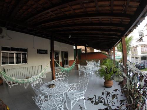 沃尔塔雷东达Pousada Casagrande - São João的庭院配有白色的椅子、桌子和吊床