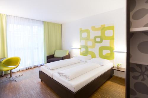 多瑙河畔克雷姆斯克莱姆斯酒店的一间卧室配有一张大床和一张黄色椅子