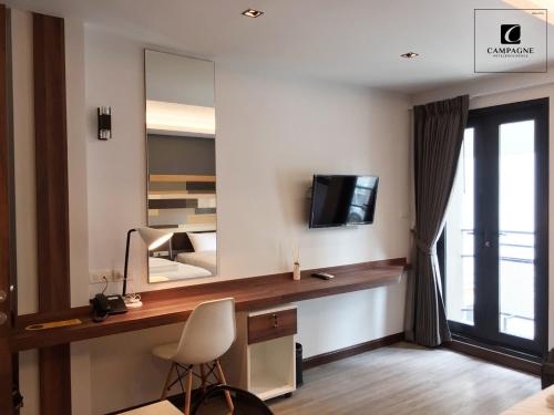 巴吞他尼Campagne Hotel and Residence - SHA Plus的一间卧室配有一张桌子、一台电视和一面镜子